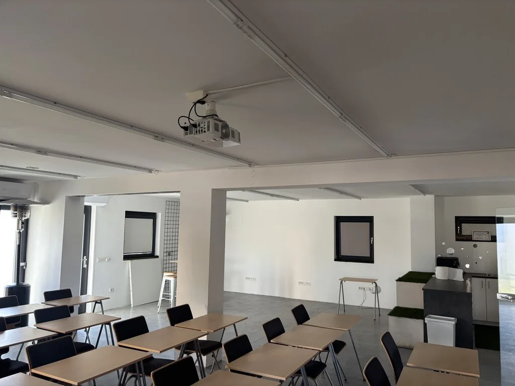 Dvorana: učionički raspored sa stolovima i stolicama, stropni projektor i kuhinjski kutak