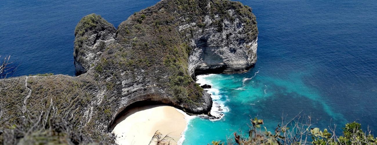 Strma litica iznad tirkizne uvale s bijelom pješčanom plažom