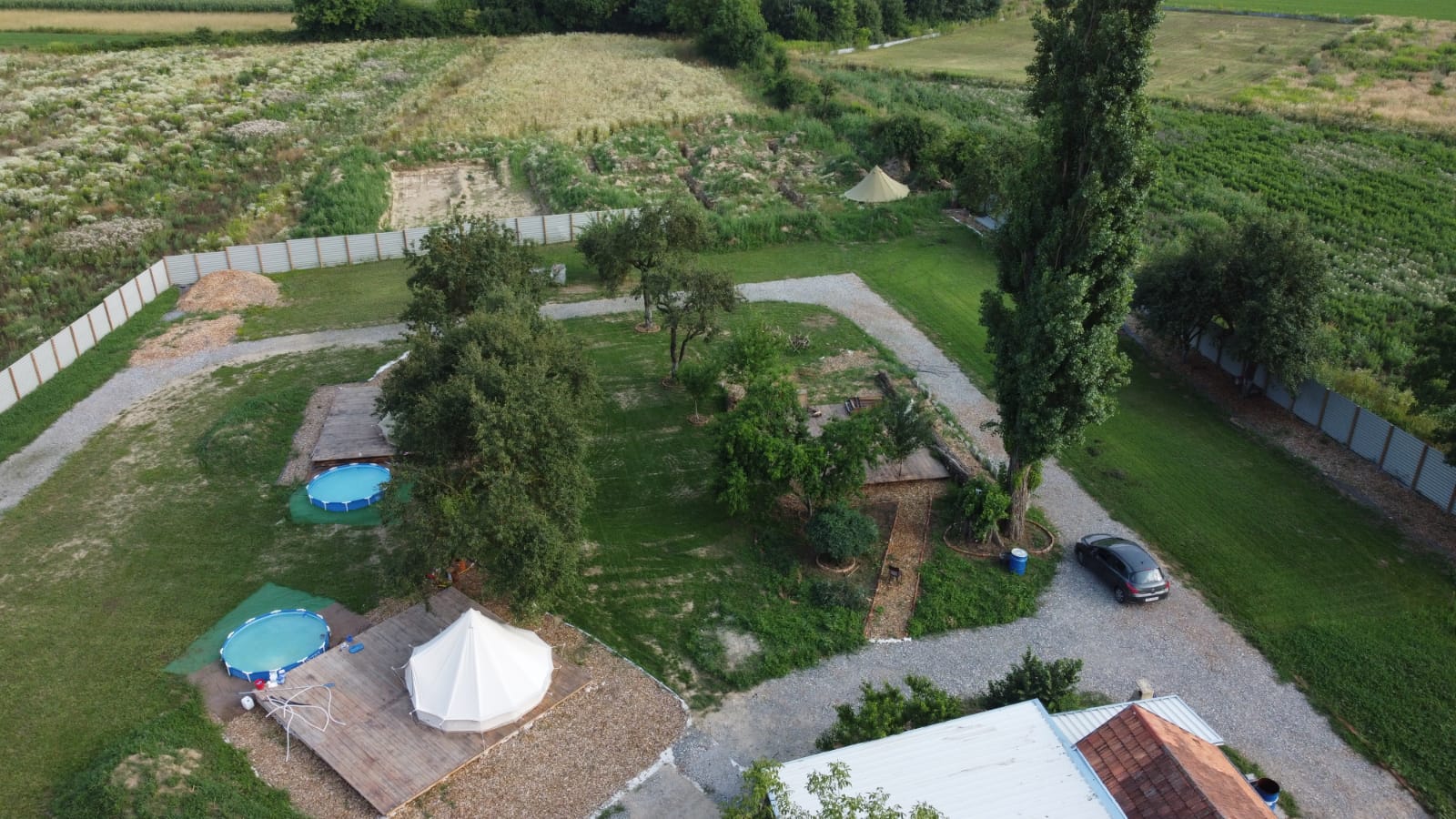 Aerial view of the camp with a white tent on a deck and two pools